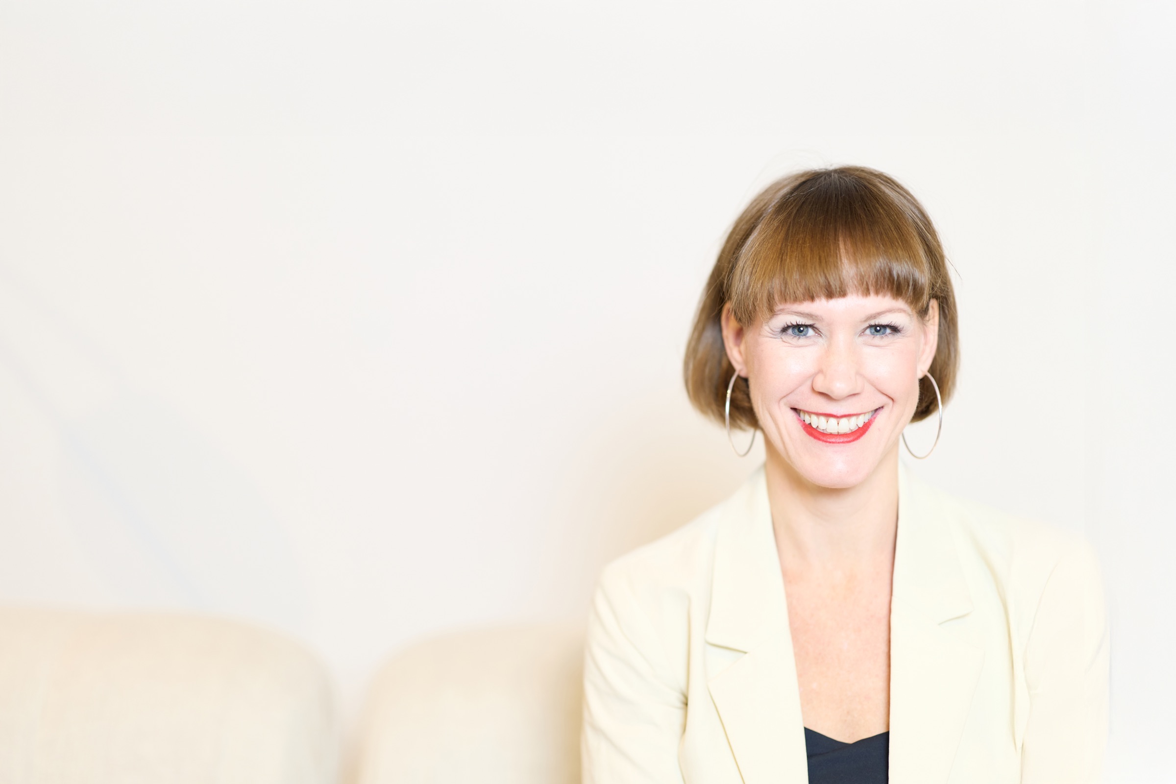 Kim Marie Bischoff sitzt in hellem Anzug mit Laptop
